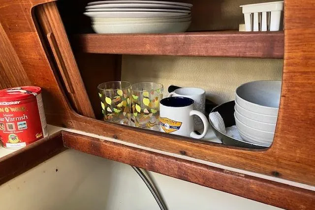 Slide: The Image of Wooden cabinet with dishes and mugs inside a 1989 Sabre 30 boat kitchen. - 21