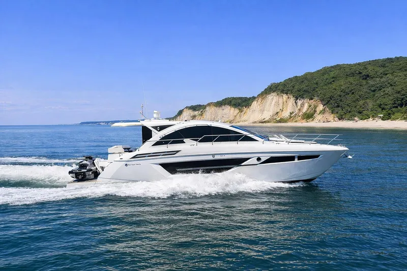 The Image of 2018 Cruisers Yachts 50 Cantius cruising near scenic coastline under clear blue sky. - 0