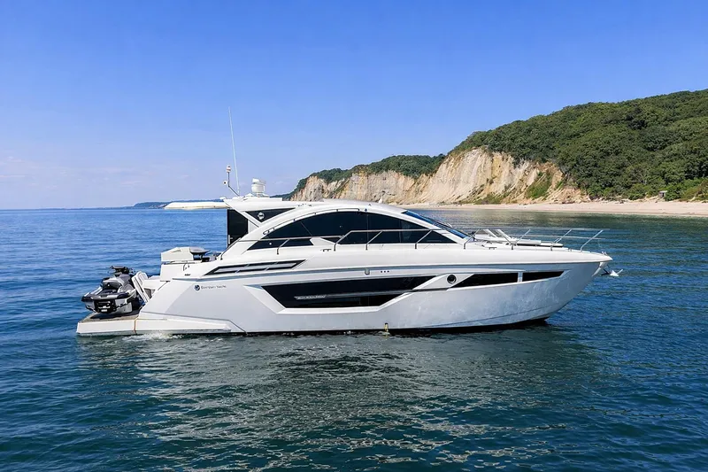 Slide: The Image of 2018 Cruisers Yachts 50 Cantius on serene water with scenic coastal backdrop. - 2