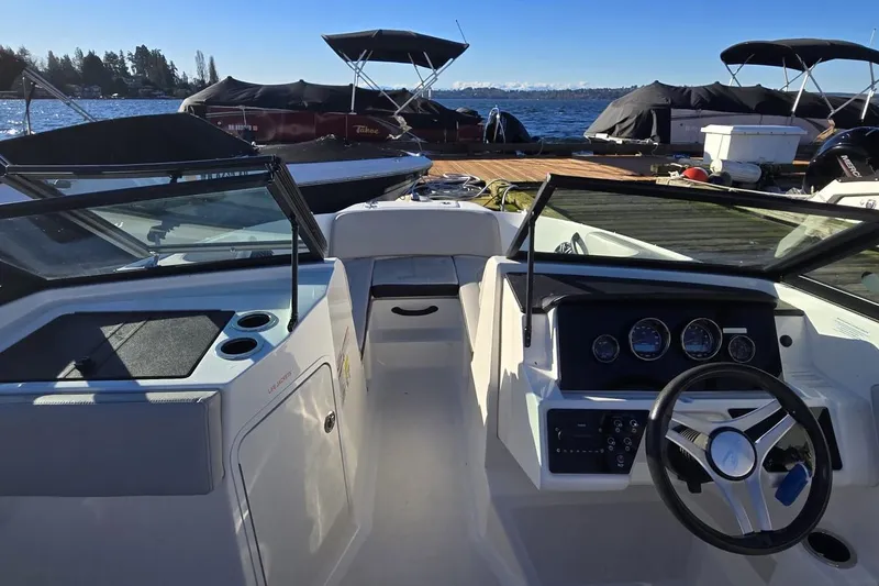 Slide: The Image of 2023 Sea Ray SPX 210 Outboard boat interior with dashboard and steering wheel, docked by the water. - 16