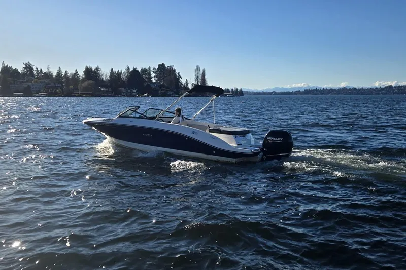 Slide: The Image of 2023 Sea Ray SPX 210 Outboard cruising on a scenic lake under clear skies. - 2