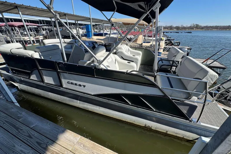 Slide: The Image of 2024 Crest Classic LX 220 SLRC pontoon boat docked at marina, featuring spacious seating. - 14