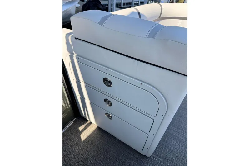 Slide: The Image of 2024 Crest Classic LX 220 SLRC boat interior with white cushioned seating and storage drawers. - 27