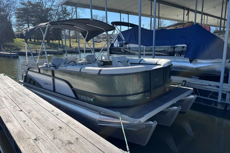 Slide: The Image of 2024 Crest Classic LX 220 SLRC pontoon boat docked under a canopy. - 7