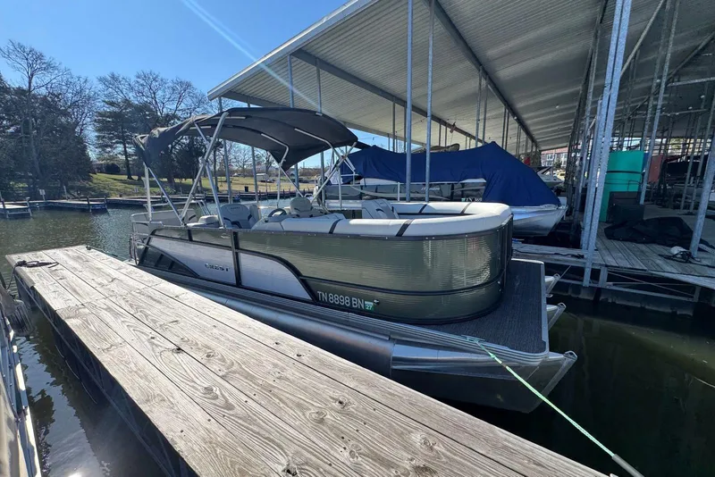 Slide: The Image of 2024 Crest Classic LX 220 SLRC pontoon boat docked under a covered marina. - 8