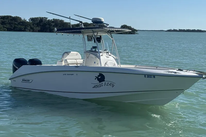 Slide: The Image of 2006 Boston Whaler 270 Outrage boat on calm water, featuring twin Mercury engines. - 0