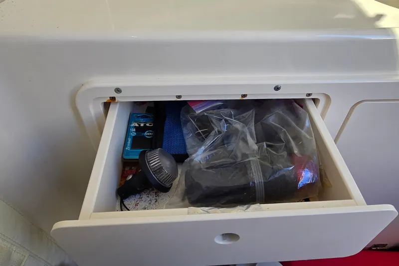 Slide: The Image of Open storage compartment on 2006 Boston Whaler 270 Outrage, containing various boating accessories. - 24