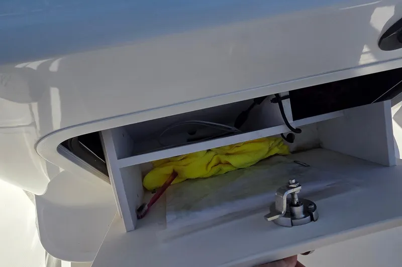 Slide: The Image of Storage compartment on a 2006 Boston Whaler 270 Outrage, containing a yellow cloth and a toothbrush. - 7