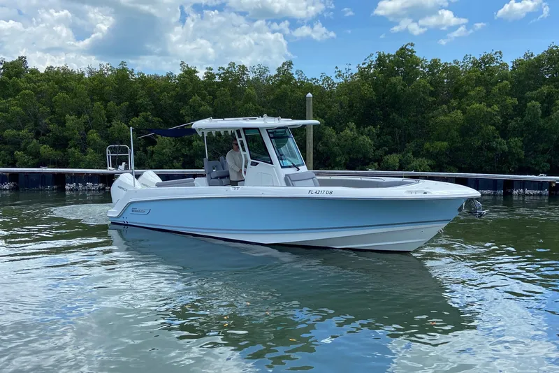 The Image of 2025 Boston Whaler 280 Outrage boat on calm water, surrounded by lush greenery. - 0