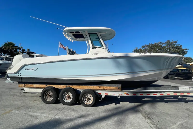 Slide: The Image of 2025 Boston Whaler 280 Outrage boat on a trailer under clear blue sky. - 17