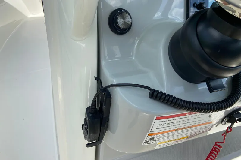 Slide: The Image of Control panel of 2025 Boston Whaler 280 Outrage boat with coiled cable and warning labels. - 39