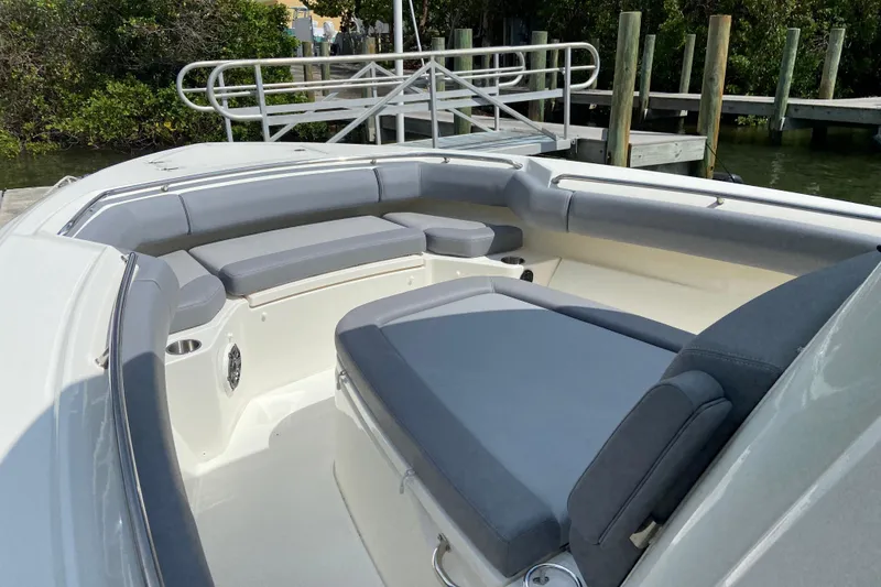 Slide: The Image of 2025 Boston Whaler 280 Outrage boat interior with cushioned seating and dock view. - 49