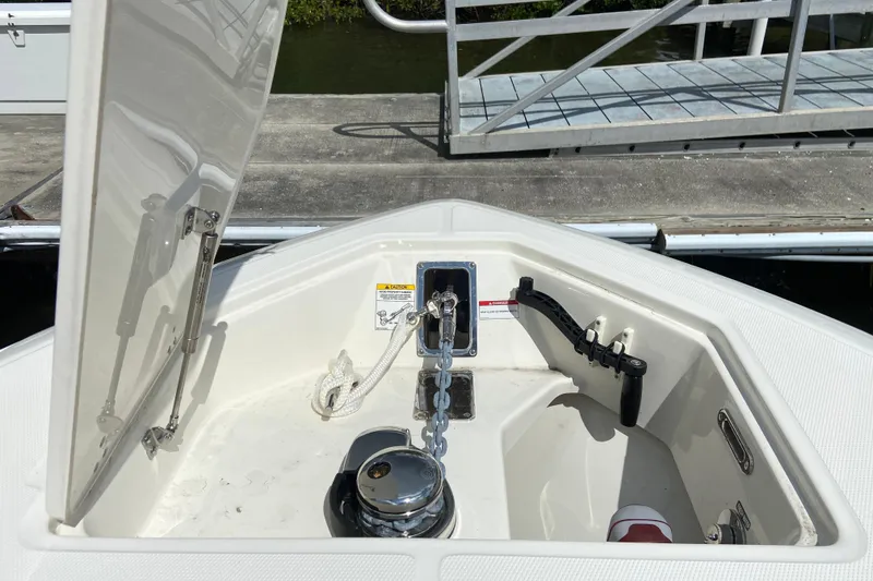 Slide: The Image of 2025 Boston Whaler 280 Outrage anchor compartment with open hatch and dock in background. - 53