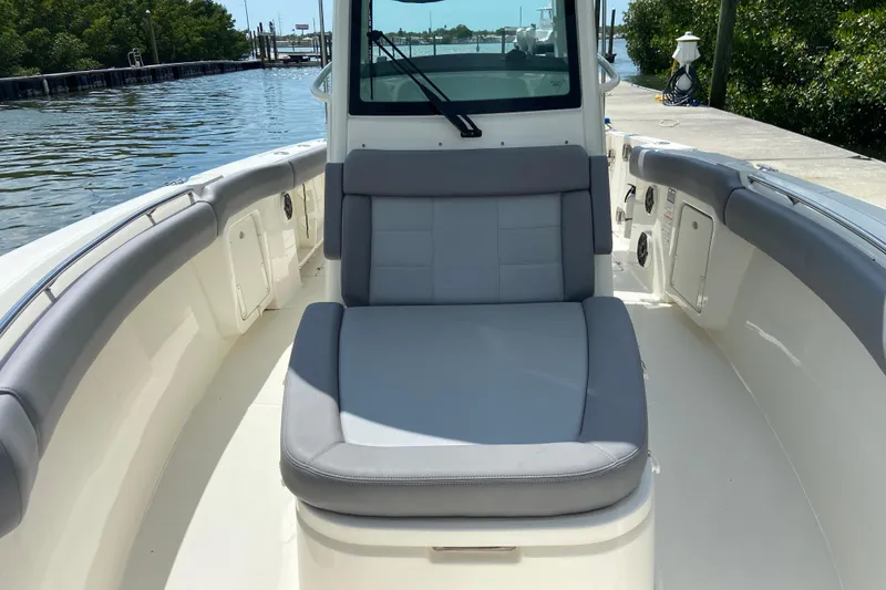 Slide: The Image of 2025 Boston Whaler 280 Outrage boat interior with cushioned seating, docked by the water. - 56