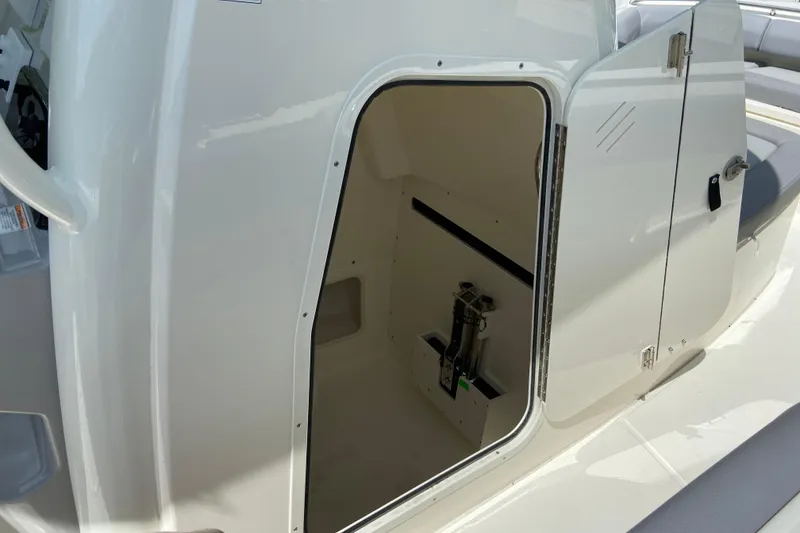 Slide: The Image of 2025 Boston Whaler 280 Outrage storage compartment with open door, showcasing interior space. - 60