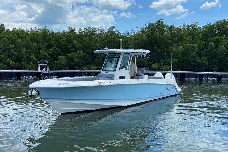 Slide: The Image of 2025 Boston Whaler 280 Outrage boat on calm water near a dock. - 8