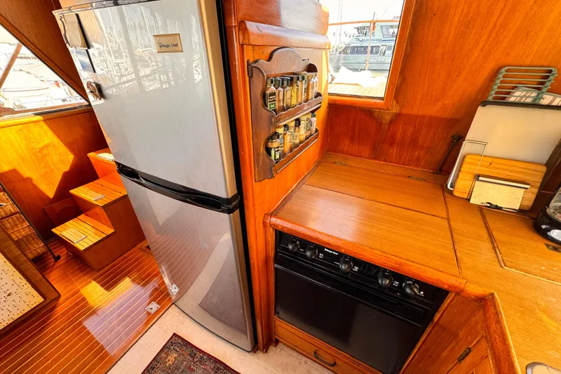 Slide: The Image of 1983 Sea Ranger 45 Sun Deck kitchen with fridge, spice rack, and wooden cabinetry. - 10