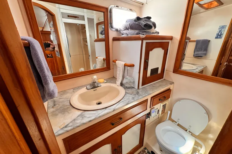 Slide: The Image of 1983 Sea Ranger 45 Sun Deck bathroom with marble countertop, sink, and wooden cabinetry. - 14