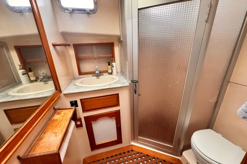 Slide: The Image of 1983 Sea Ranger 45 Sun Deck bathroom with sink, shower, and wooden accents. - 18