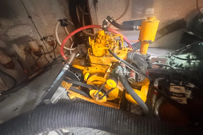 Slide: The Image of Engine room of 1983 Sea Ranger 45 Sun Deck with visible yellow machinery and hoses. - 27