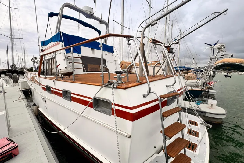 Slide: The Image of 1983 Sea Ranger 45 Sun Deck yacht docked at marina, featuring wooden accents and blue canopy. - 30
