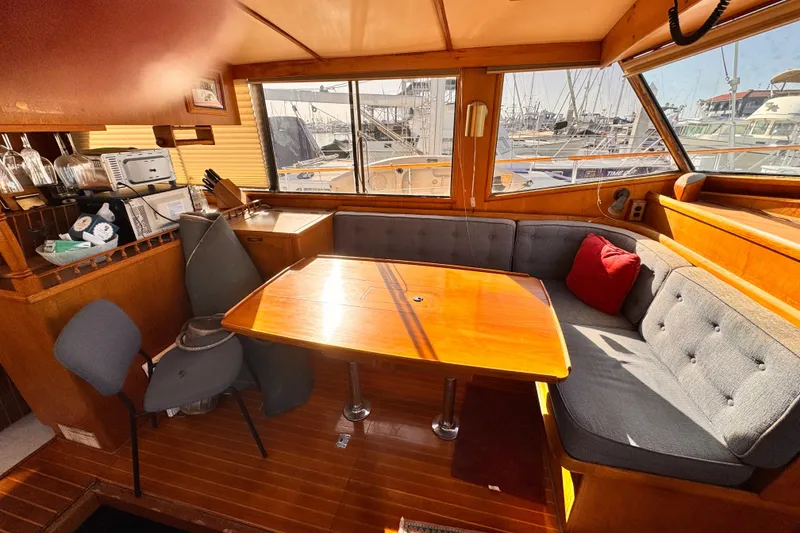 Slide: The Image of 1983 Sea Ranger 45 Sun Deck interior with cozy seating and wooden table, marina view. - 5