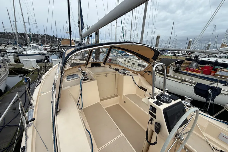 Slide: The Image of 2025 Island Packet 349 sailboat cockpit at marina, showcasing helm and seating area. - 13