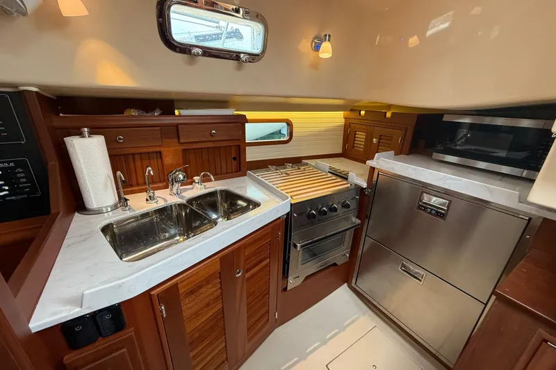 Slide: The Image of Luxurious 2025 Island Packet 349 yacht kitchen with modern appliances and elegant wood cabinetry. - 25