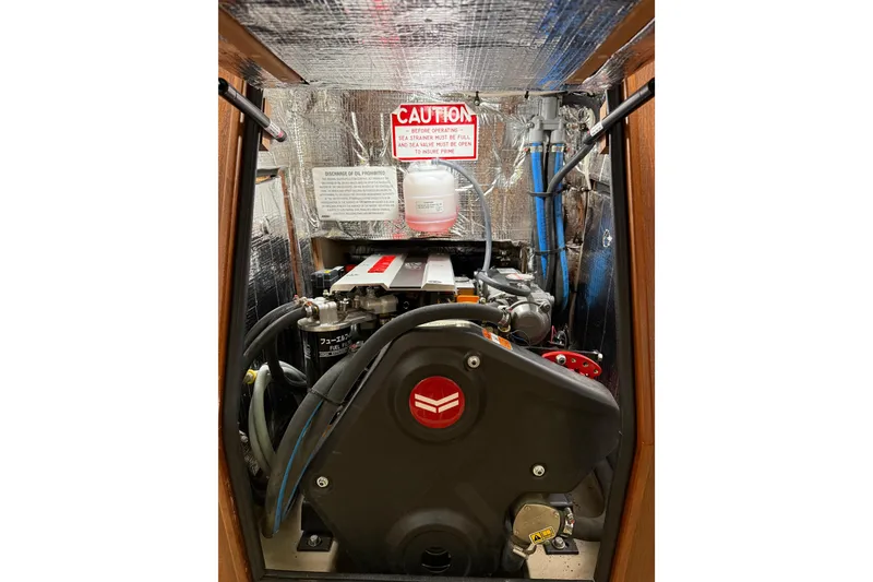 Slide: The Image of Engine compartment of 2025 Island Packet 349 sailboat, featuring mechanical components and caution signage. - 32