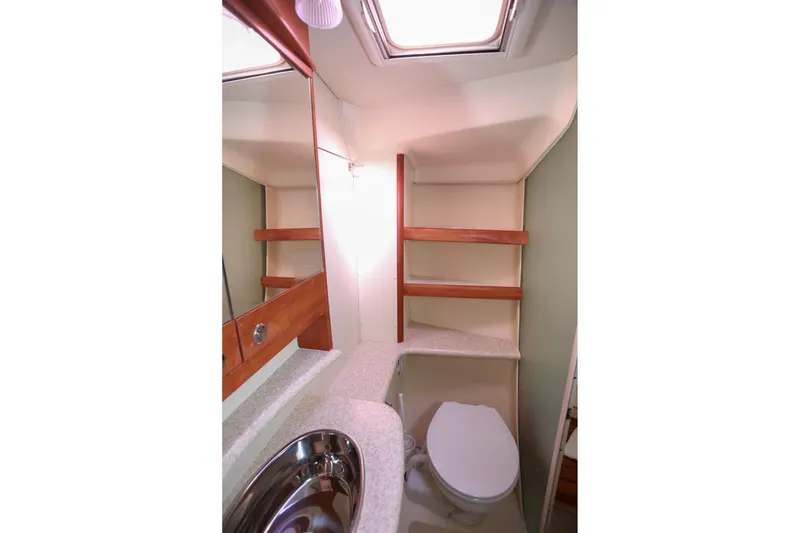 Slide: The Image of 2009 Hunter 45 Center Cockpit bathroom with sink, toilet, and wooden shelving. - 37
