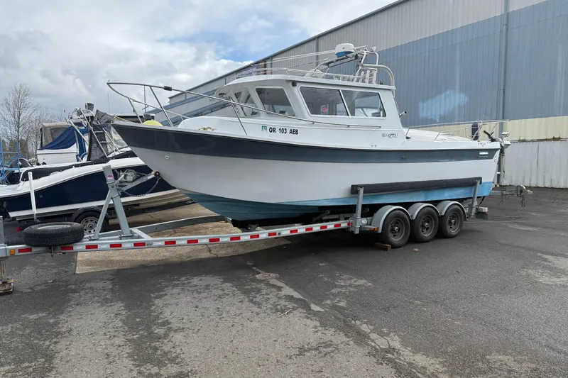 The Image of 1999 SeaSport Seamaster 2700 boat on a trailer, parked outdoors near a warehouse. - 0