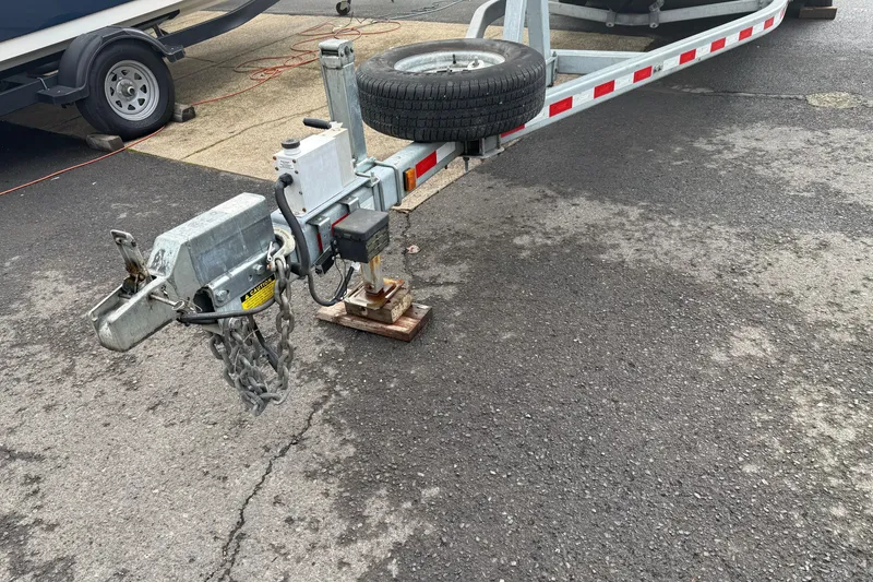 Slide: The Image of Trailer hitch of a 1999 SeaSport Seamaster 2700 on asphalt, with spare tire attached. - 1