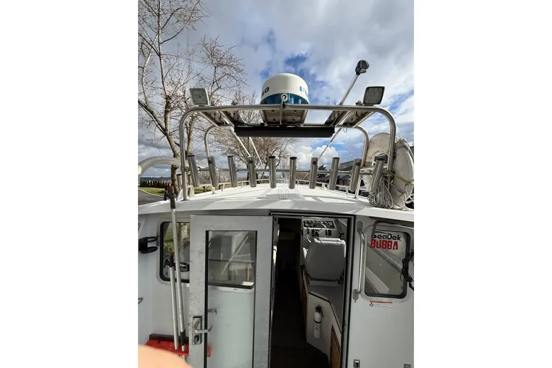 Slide: The Image of 1999 SeaSport Seamaster 2700 boat with fishing rod holders and radar, under cloudy sky. - 12