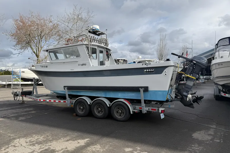 Slide: The Image of 1999 SeaSport Seamaster 2700 boat on trailer, parked outdoors under cloudy sky. - 5