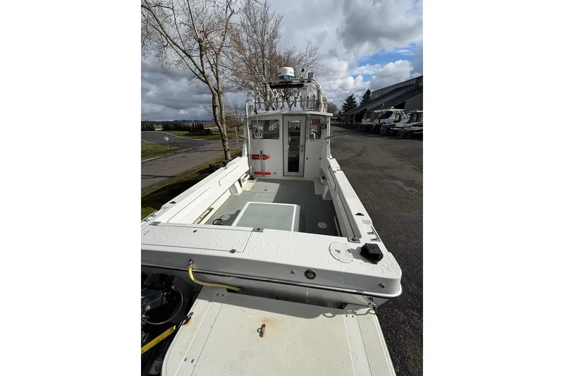 Slide: The Image of 1999 SeaSport Seamaster 2700 boat with spacious deck, docked under cloudy skies. - 6