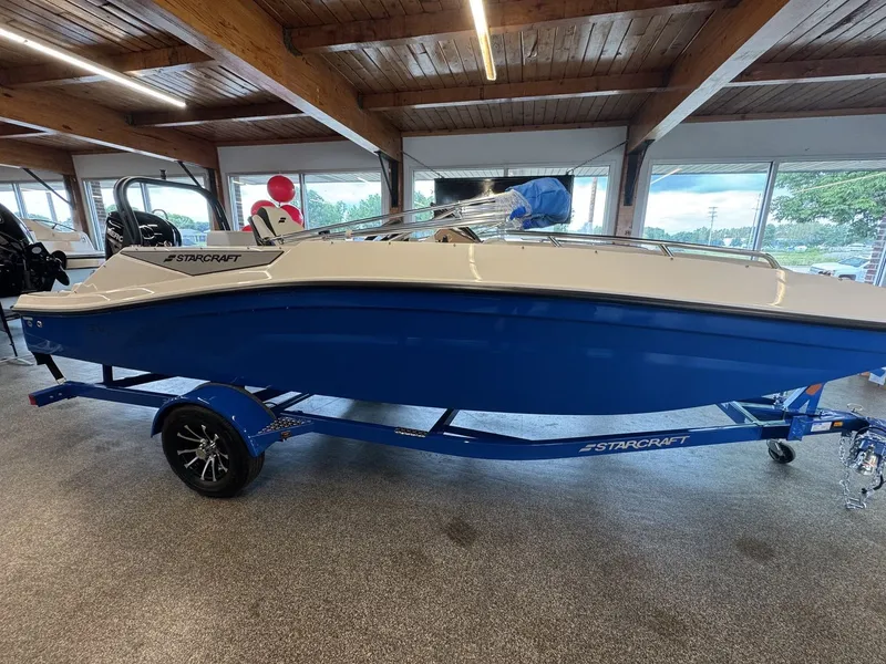 Slide: The Image of A blue and white Starcraft 181SVOB boat from 2026 sits on a trailer in a showroom. - 0