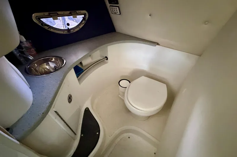 Slide: The Image of 2007 Cobalt 302 boat bathroom with sink, toilet, and porthole window. - 31