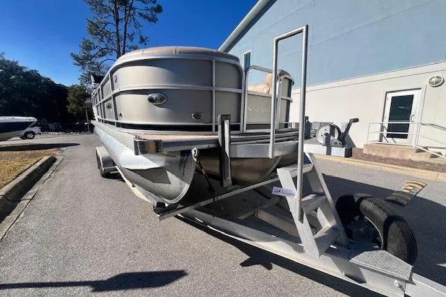 Slide: The Image of 2013 South Bay 722RS pontoon boat on trailer, parked outdoors near a building. - 6
