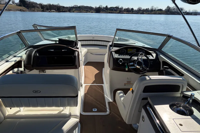 Slide: The Image of 2012 Cobalt A28 boat interior with steering wheel, dashboard, and seating on a calm lake. - 15