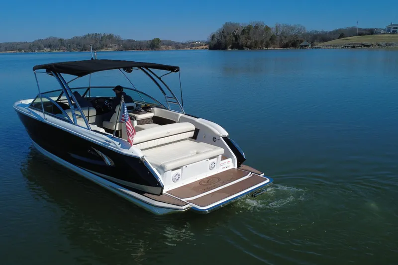 Slide: The Image of 2012 Cobalt A28 boat cruising on a serene lake under clear blue skies. - 2
