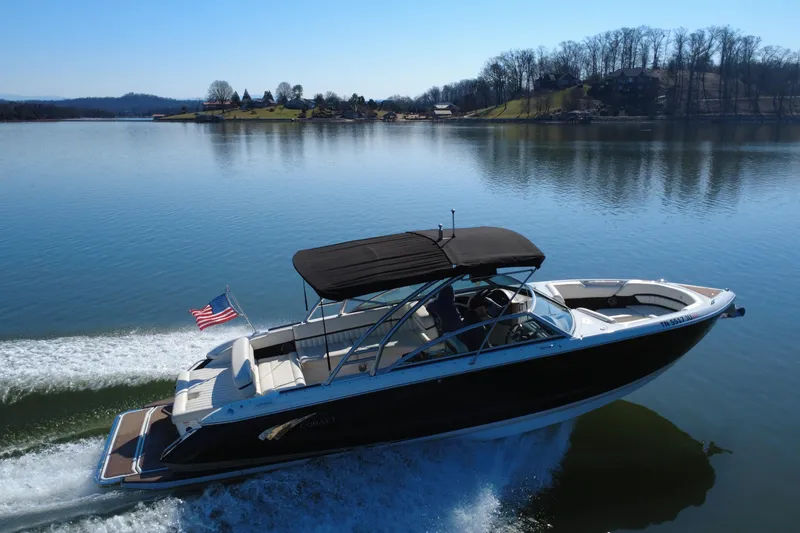Slide: The Image of 2012 Cobalt A28 boat cruising on a serene lake with American flag. - 6