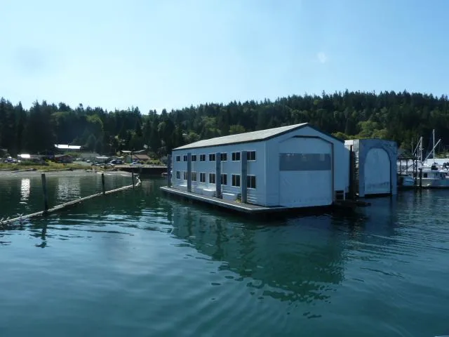 Slide: The Image of Large floating boathouse on calm water, surrounded by forest. - 3