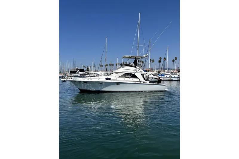 Slide: The Image of 1990 Trojan 40 Sport Fisherman boat on calm water, clear sky background. - 1