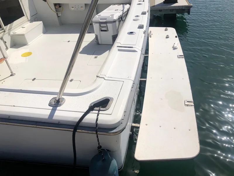 Slide: The Image of 1990 Trojan 40 Sport Fisherman boat docked, featuring spacious deck and swim platform. - 12