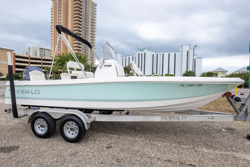 The Image of 2017 Robalo 206 Cayman boat on trailer, parked near tall buildings. - 0