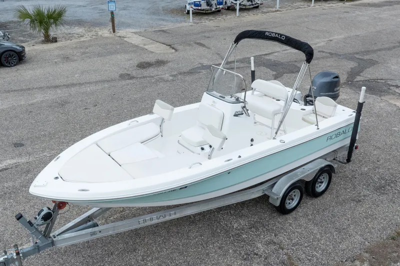 Slide: The Image of 2017 Robalo 206 Cayman boat on trailer, white and light blue, parked outdoors. - 2
