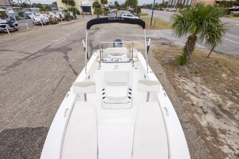 Slide: The Image of 2017 Robalo 206 Cayman boat with seating, parked near palm trees and road. - 24