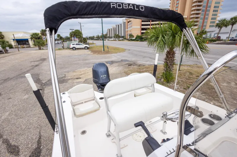 Slide: The Image of 2017 Robalo 206 Cayman boat with Yamaha 115 engine, parked near palm trees and buildings. - 26