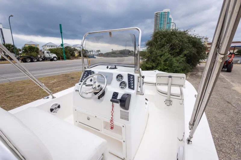 Slide: The Image of 2017 Robalo 206 Cayman boat interior with steering console and seating, parked near a road. - 34
