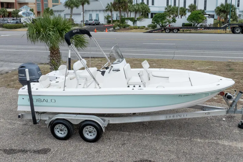 Slide: The Image of 2017 Robalo 206 Cayman boat on trailer, parked near a road with palm trees. - 8